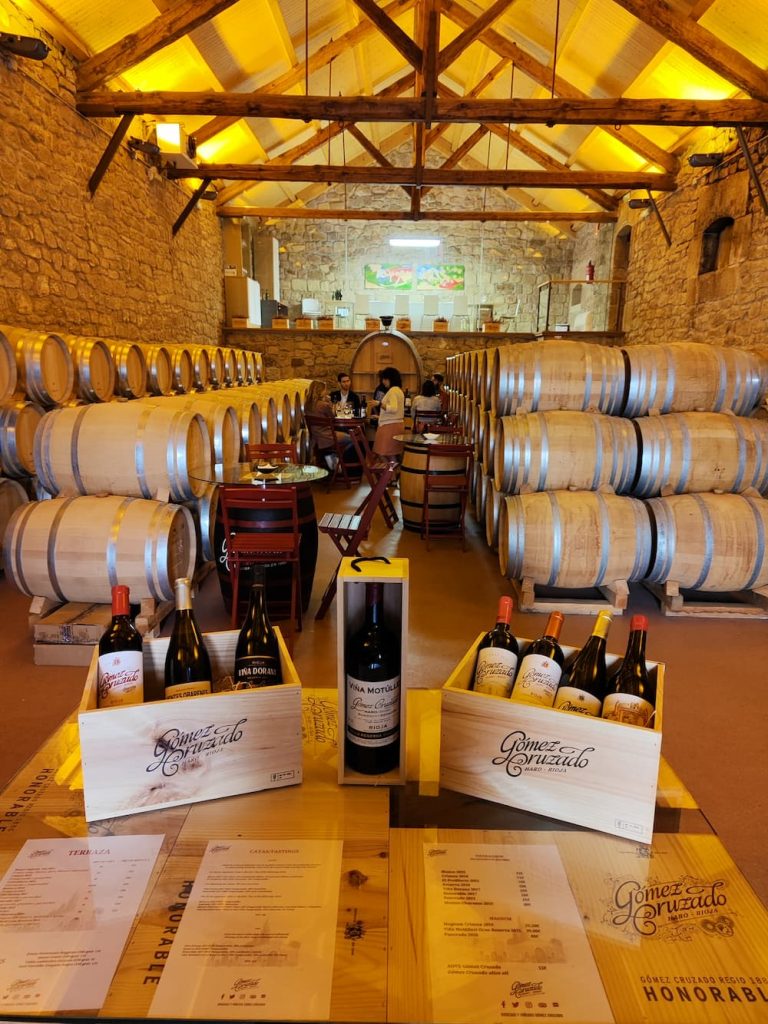 Wooden crates of Gomez Cruzado wines displayed in a historic stone barrel cellar in Haro, the heart of the Rioja wine region, during a North Coast Tours premium wine excursion.
